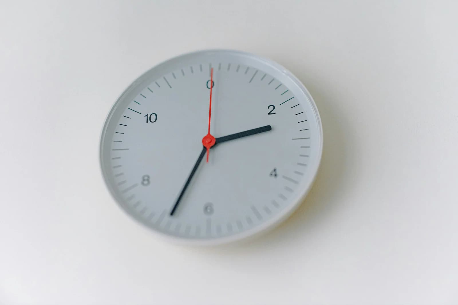 A clean, minimalist white wall clock with a distinct red second hand, representing fast lead response times and around-the-clock small business availability.