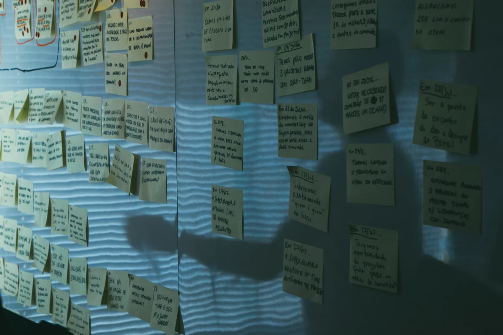 A whiteboard covered in rows of yellow sticky notes filled with handwritten project planning notes, illustrating a GEO vs SEO strategic brainstorming session.