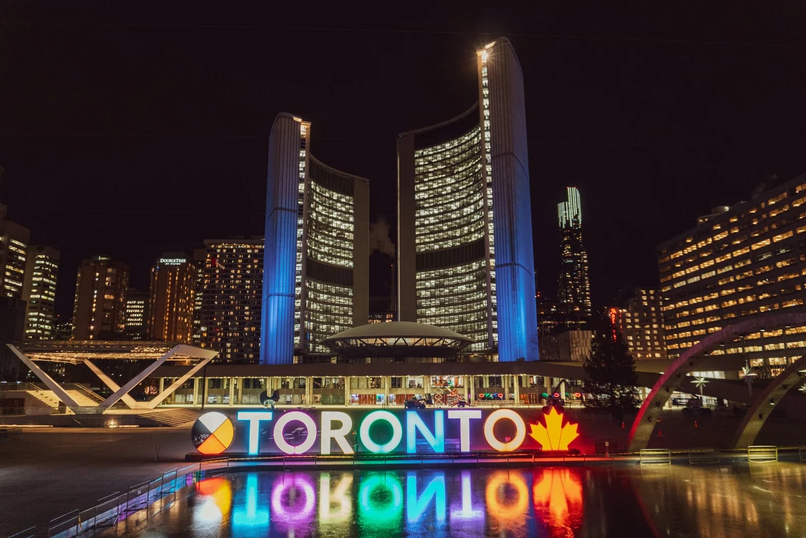 The iconic, brightly lit Toronto sign reflecting in the water at Nathan Phillips Square at night, showcasing the innovative spirit of a Web Design Agency in Toronto.