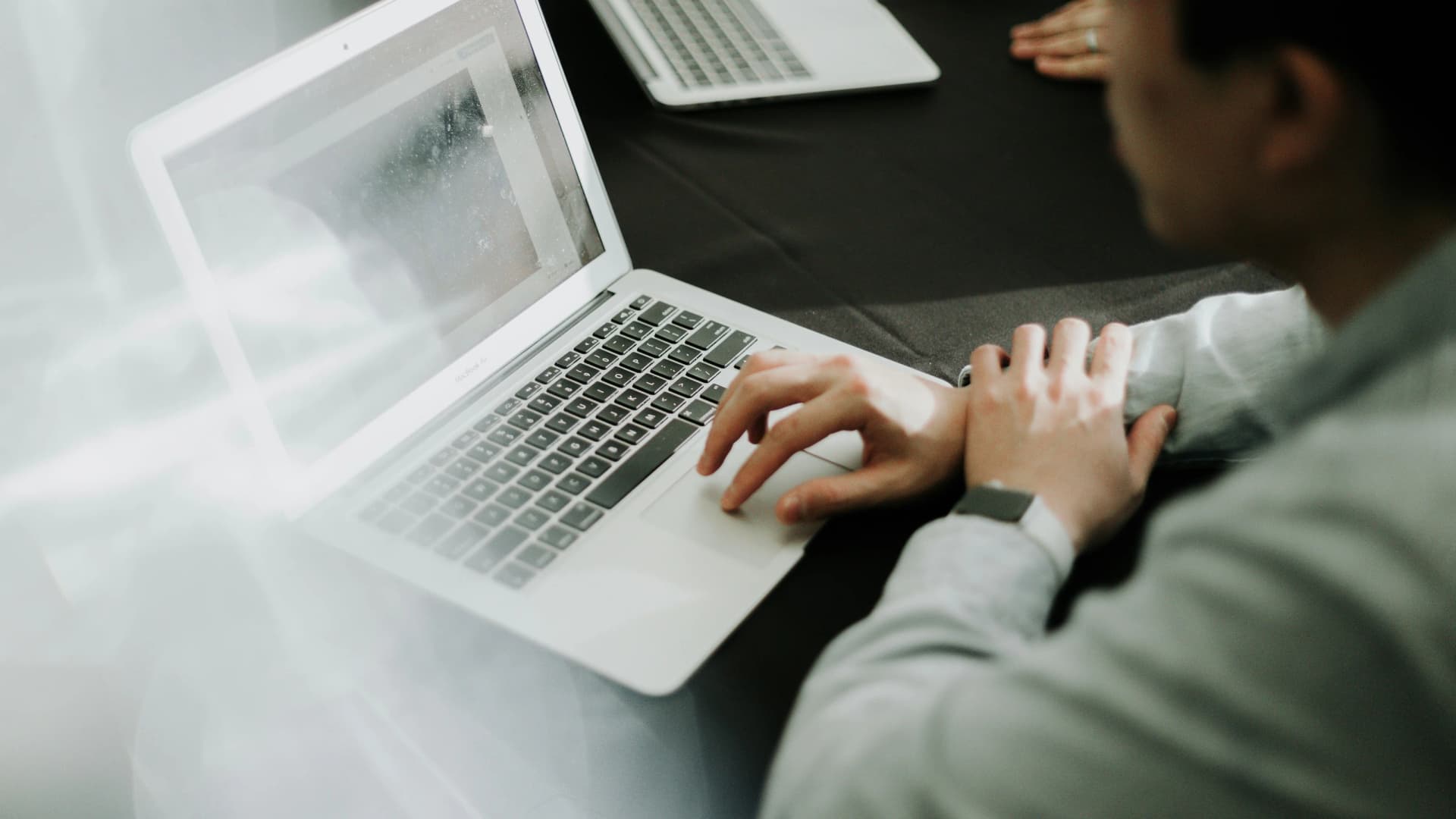 Two people reviewing website traffic on laptops during a meeting, with site visits increasing but no leads coming through.