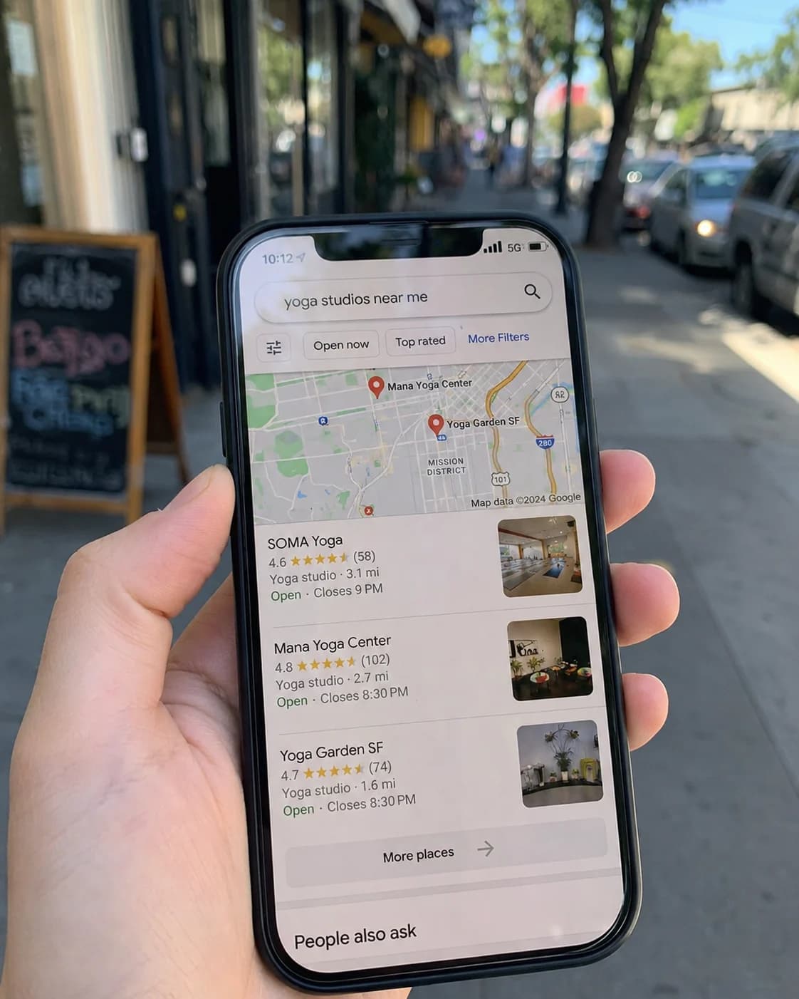 A local search for "yoga studios near me" on a phone, the discovery surface that precedes most first-visit decisions on the path to filling yoga studio classes.