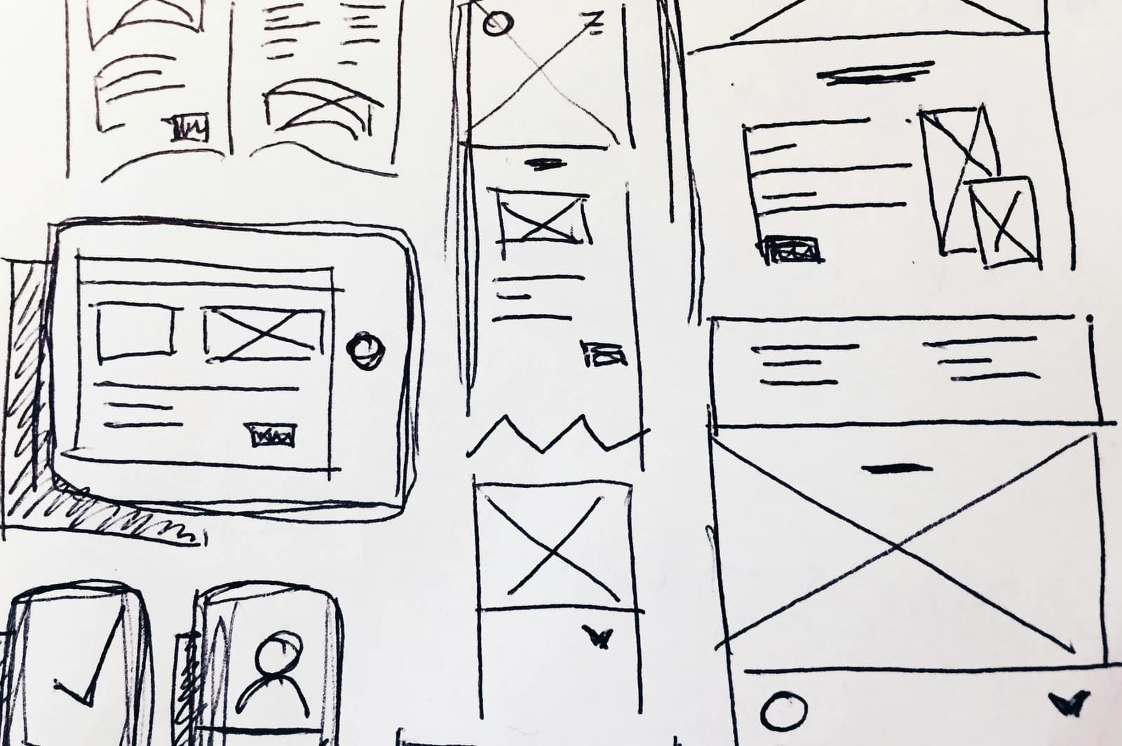 A black ink sketch on paper showing hand-drawn website wireframes and layout ideas for mobile, tablet, and desktop screens, representing the structural layout changes identified during a website audit checklist review.