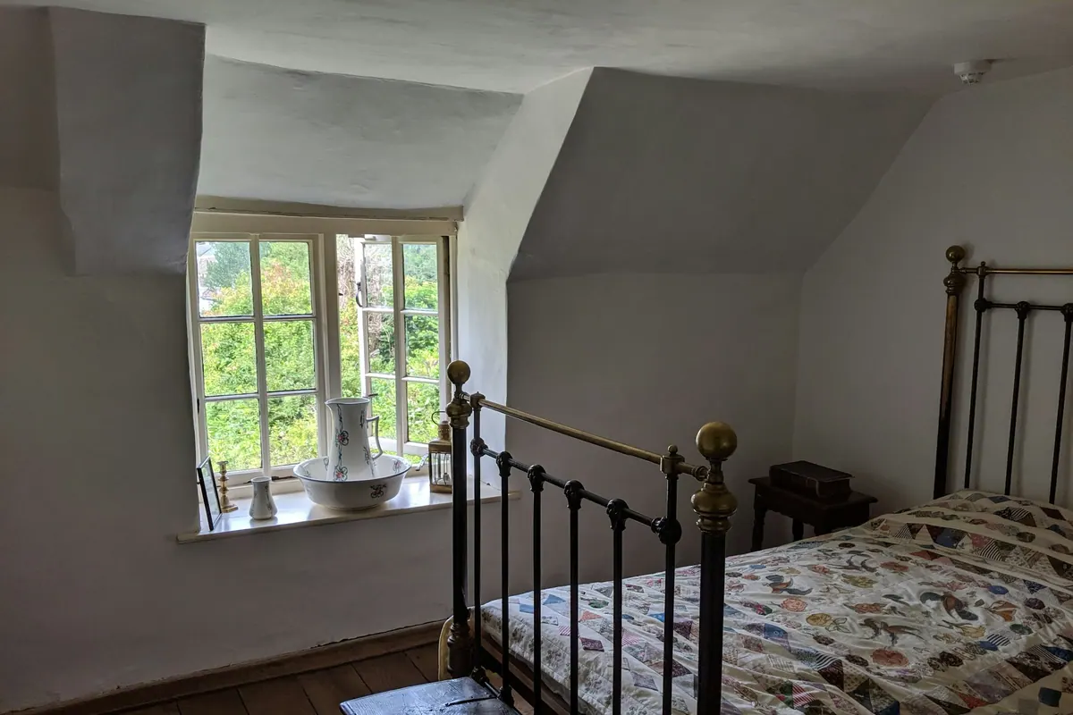 A room with an original metal bed frame beside a window
