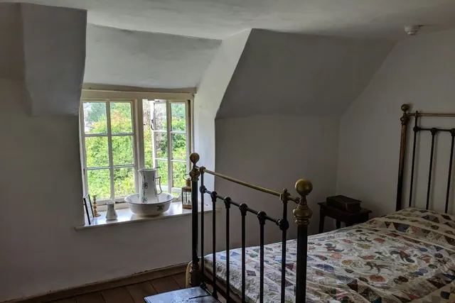 A room with an original metal bed frame beside a window