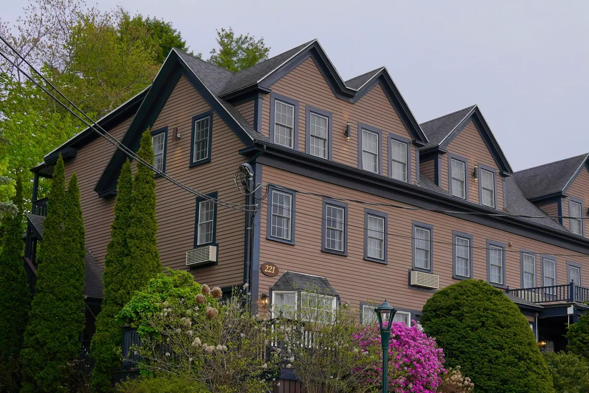 A large shingled inn building framed by greenery